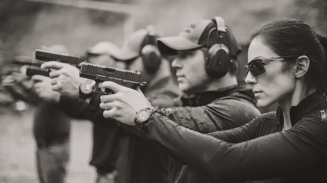 Students in eye and ear protection firing pistols on a training line
